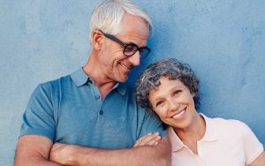 An elderly couple beams at the camera, their smiles capturing a moment of love and togetherness.