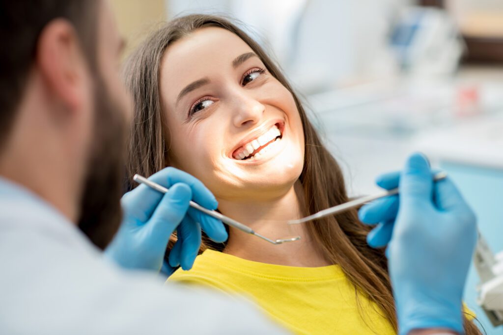 Portrait of a woman with toothy smile sitting during examination at the dental office.