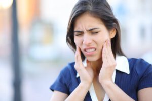 A young woman clutching her jaw in pain.