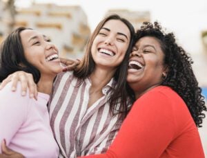 A group of women smiling and laughing together with enhanced teeth.